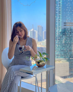 Woman drinking coffee sitting by window