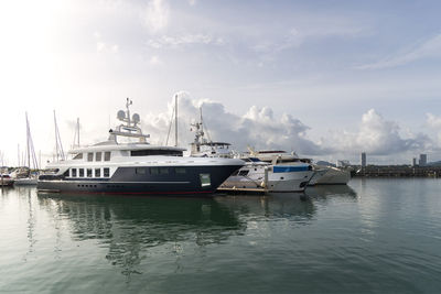 Boats moored at harbor against sky