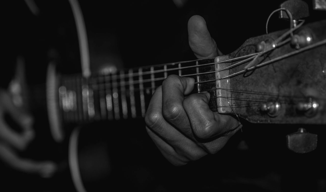 CLOSE-UP OF MAN PLAYING GUITAR AT CAMERA