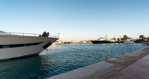 Sailboats moored on sea against clear blue sky