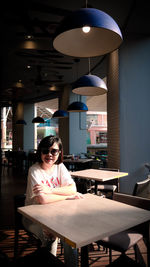 Portrait of mid adult woman sitting at table in restaurant