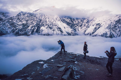 People on snowcapped mountain against sky