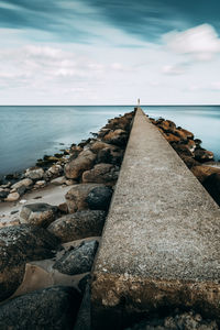 Rocks on beach against sky. long exposure of pier. 