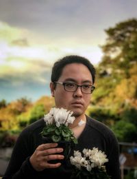 Portrait of young man holding flower