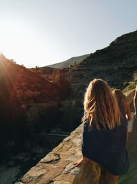 Rear view of woman walking on mountain against clear sky