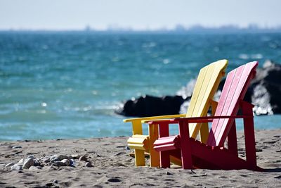 Close-up of deck chairs on beach against sky