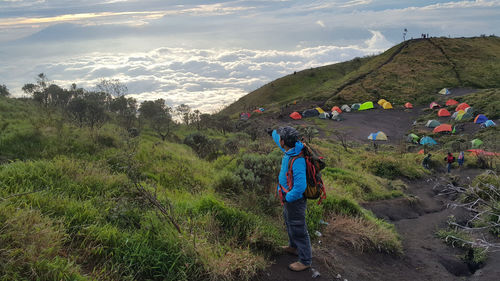 Hiker climbing mountain against cloudy sky