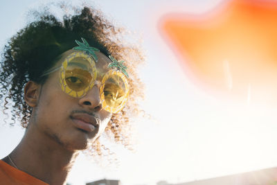 Close-up portrait of young man wearing novelty glasses against sky at music concert