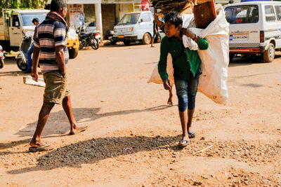 Rear view of people walking on road in city