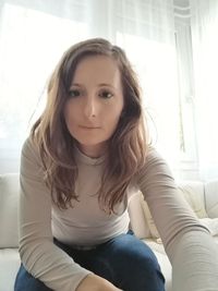 Portrait of young woman sitting on sofa at home