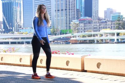 Full length of woman standing by railing in city