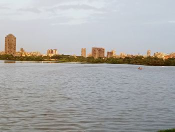 Sea by buildings in city against sky