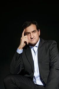 Mid adult man sitting against black background