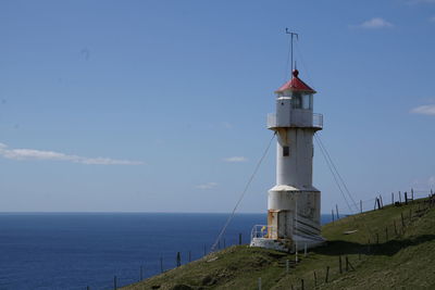 Lighthouse by sea against sky