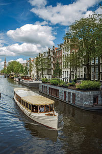 Tree-lined canal with old buildings and boats in amsterdam. the netherland capital full of canals.