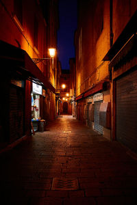Empty narrow alley along buildings at night