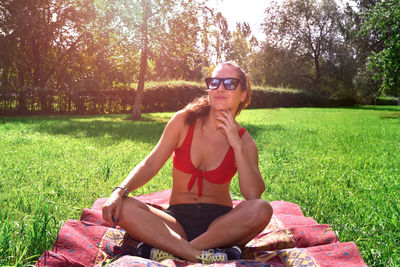 Portrait of woman wearing sunglasses while sitting at park