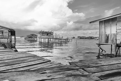 Wooden posts on pier by sea against sky