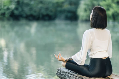 Meditation in nature. woman sitting in lotus position and meditating by the lake