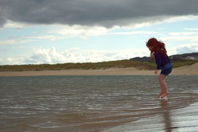 Woman standing on beach against sky