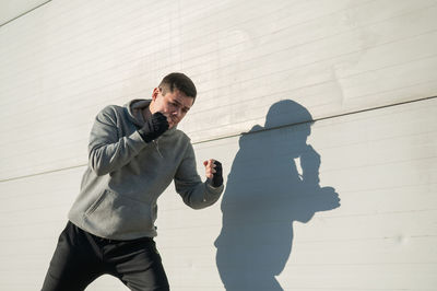 Caucasian man in hoodie is training boxing outdoors