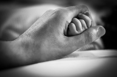 Close-up of parent holding baby hand