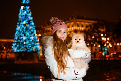 Beautiful teenage girl plays and has fun with her spitz dog, in evening on city