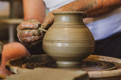 Cropped hands of potter making pot in pottery workshop