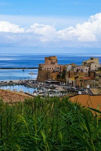 Scenic view of sea by buildings against sky