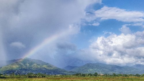 Scenic view of rainbow over mountains against sky