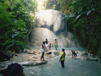 People on rocks by waterfall in forest