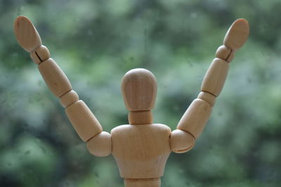 Close-up of figurine on wood against sky