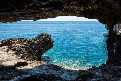 Rock formation by sea against sky