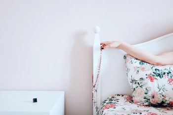 Cropped image of woman hand with bead necklace on headrest at home