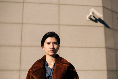 Portrait of woman standing against wall