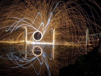 Person standing by wire wool against lake at night