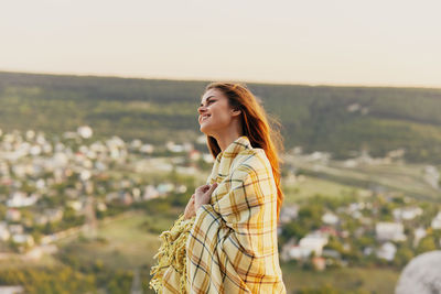 Beautiful young woman standing against sky