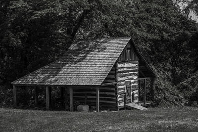 Exterior of abandoned house on field against trees in forest