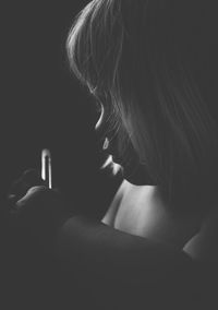 Close-up of shirtless girl sitting in darkroom