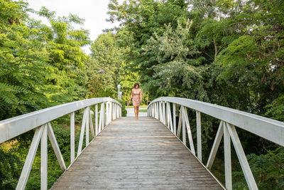 Woman on footbridge amidst trees