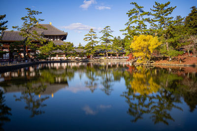 Reflection of trees and buildings in lake against sky