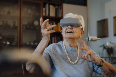 Senior woman wearing virtual reality simulator sitting at home