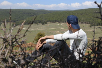 Side view of young man sitting on land