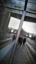 People walking on railroad track seen through window