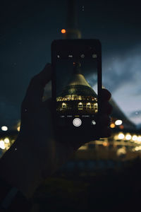 Close-up of hand photographing illuminated smart phone at night