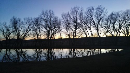 Silhouette of bare trees against sky at sunset