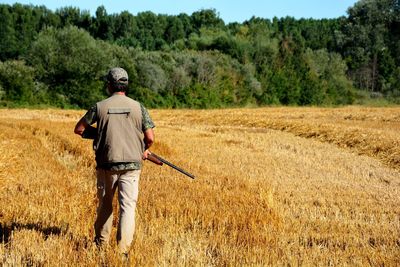 Rear view of man with gun standing on grass