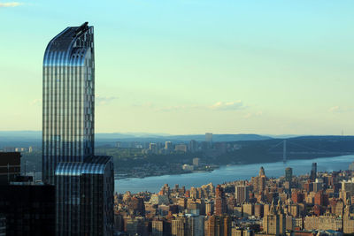 Modern building with cityscape by east river against sky