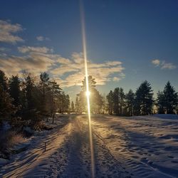 Snow covered field against sky during winter