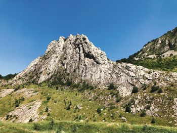 Low angle view of rocks against clear blue sky